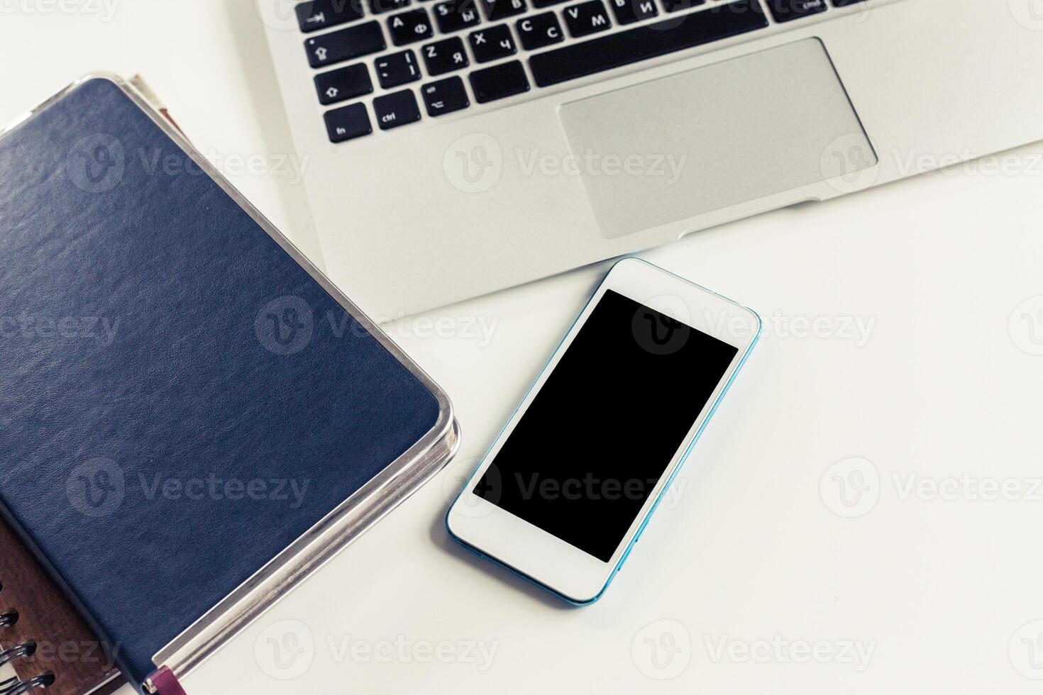 Workspace setup featuring a laptop, phone, and notebook during a daytime work session photo