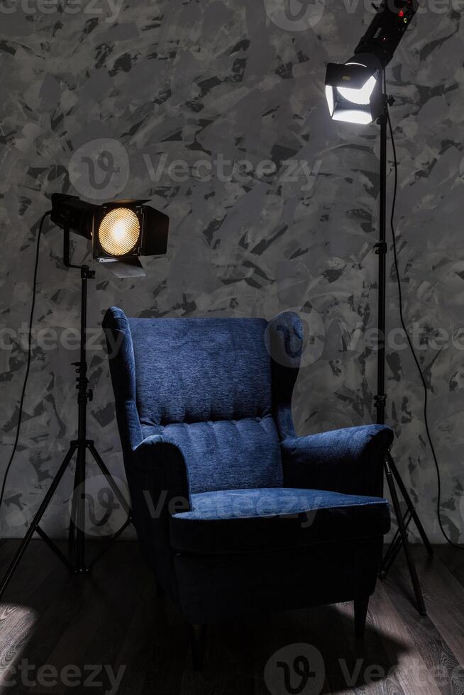 Comfortable blue armchair illuminated by studio lights in a modern, artistic interior photo