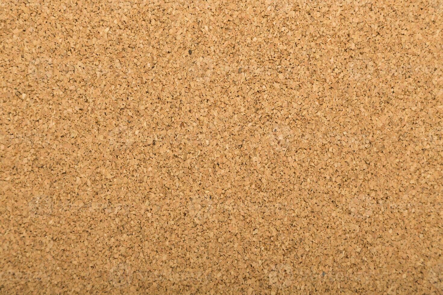 Corkboard surface with a natural texture displaying a warm and neutral color palette in a workspace setting photo