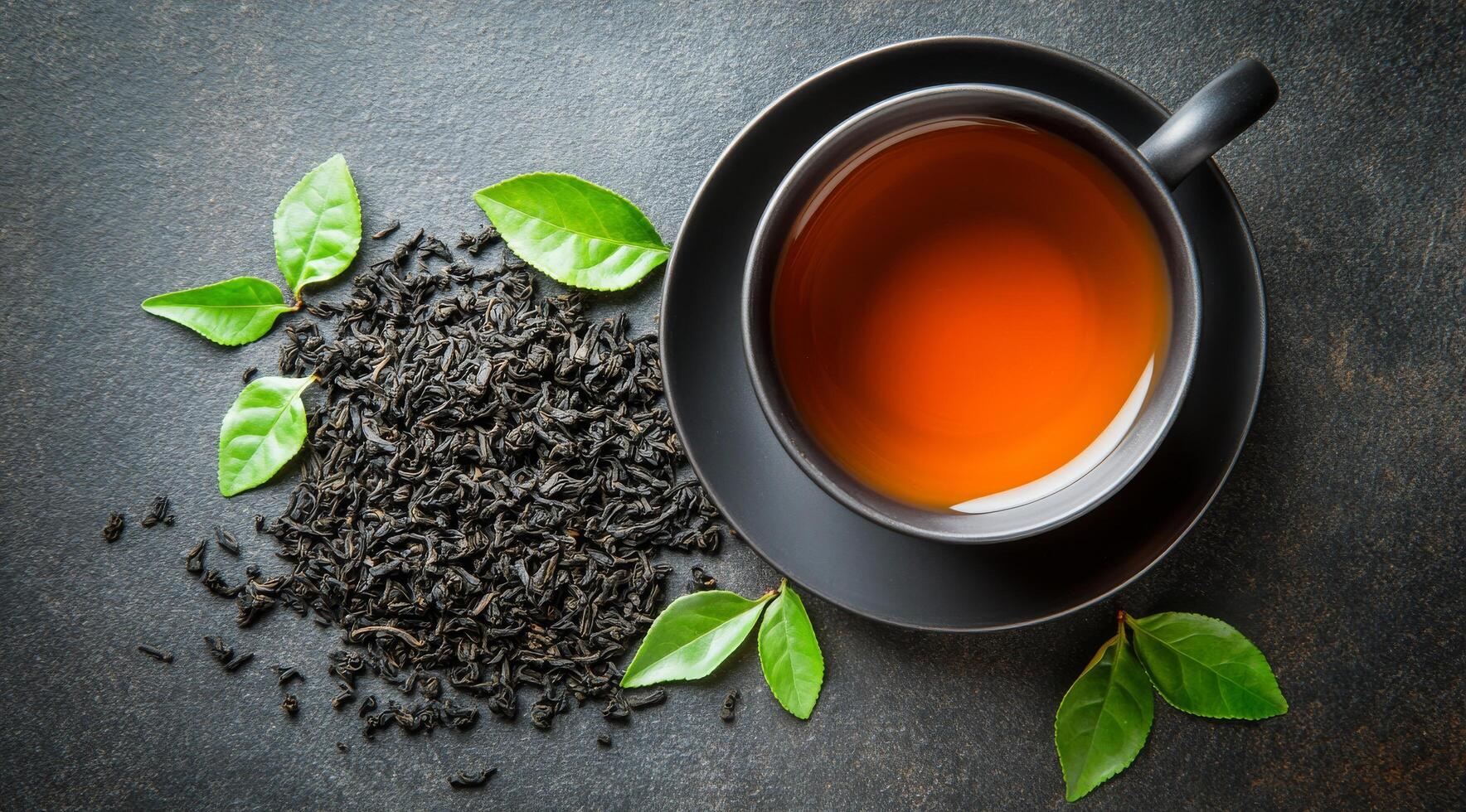 Black tea with green leaves on a dark background photo