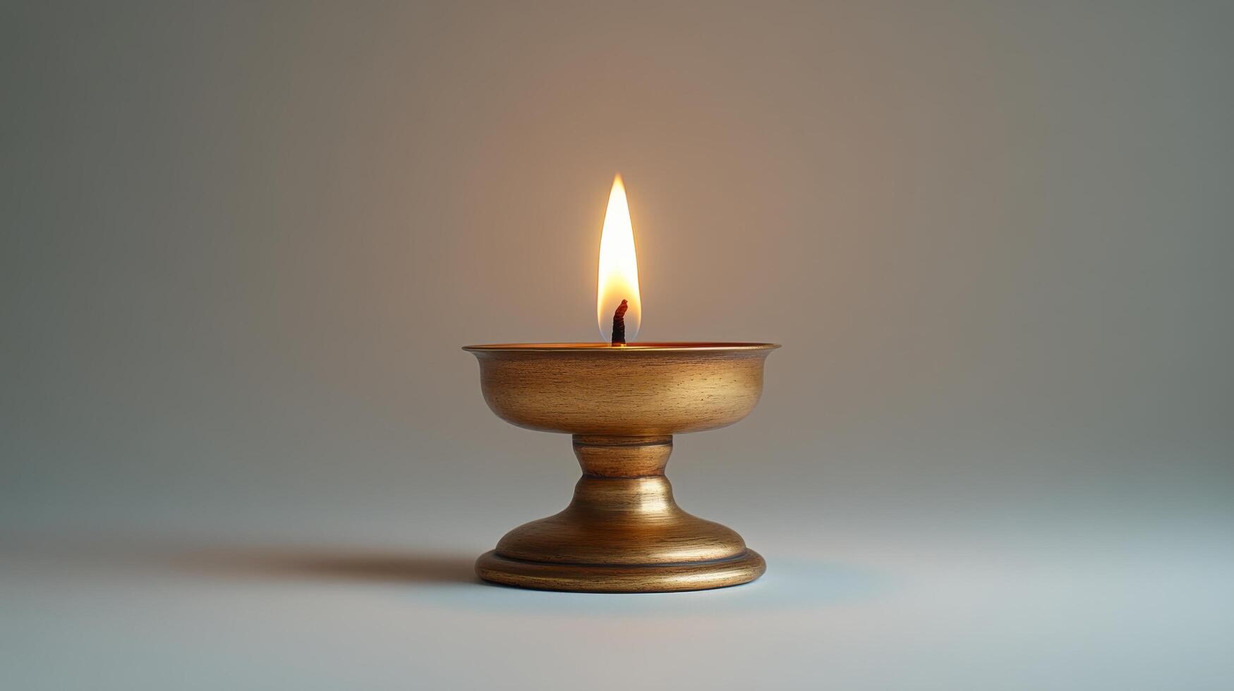A golden candle is lit on a table photo