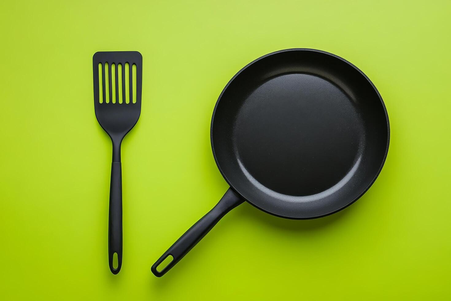 A frying pan and spatula on a green background photo