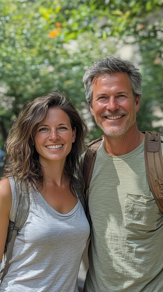 A man and woman are smiling while standing in front of trees photo