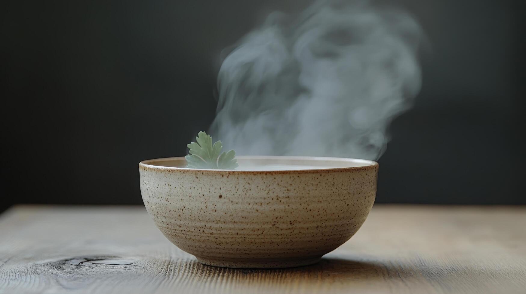 A bowl of steaming tea with a leaf in it photo