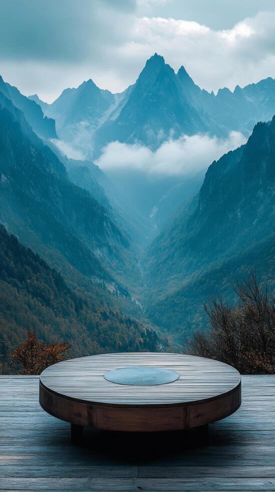 A wooden deck with a round table in front of a mountain range photo
