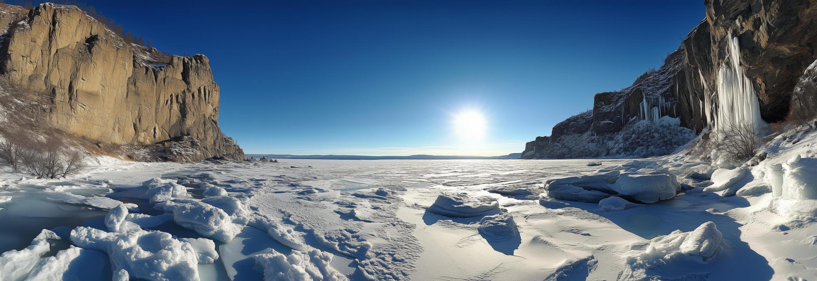 Panoramic winter view of frozen lake with towering cliffs under a clear blue sky photo