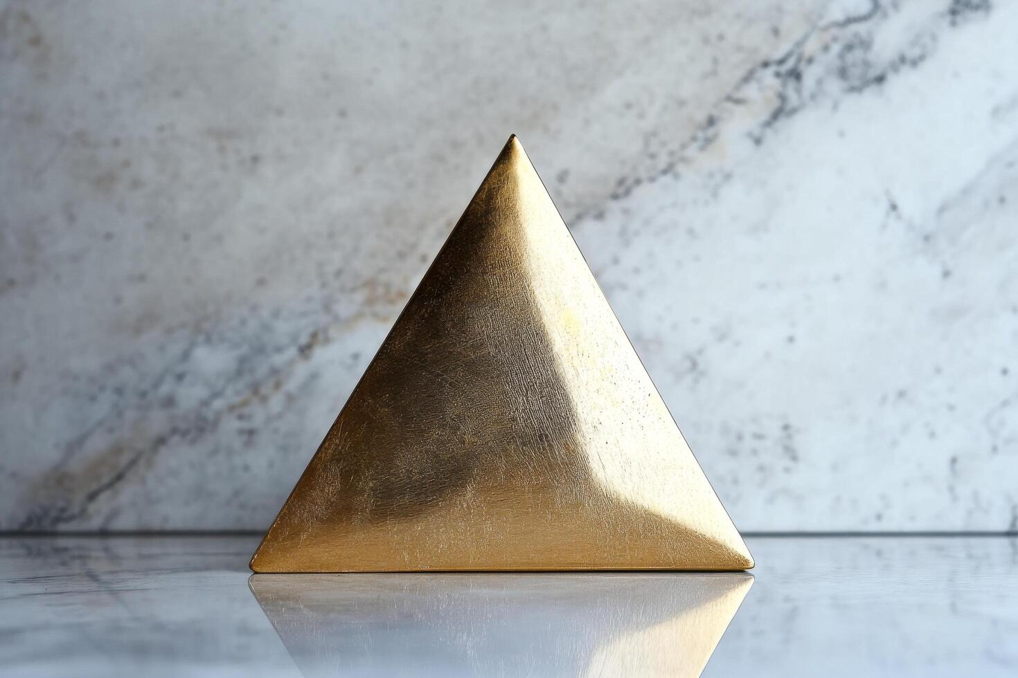 A gold triangle shaped object sitting on a marble surface photo