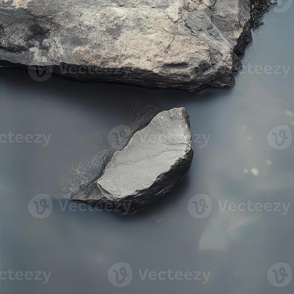 Large rocks partially submerged in a calm body of water photo
