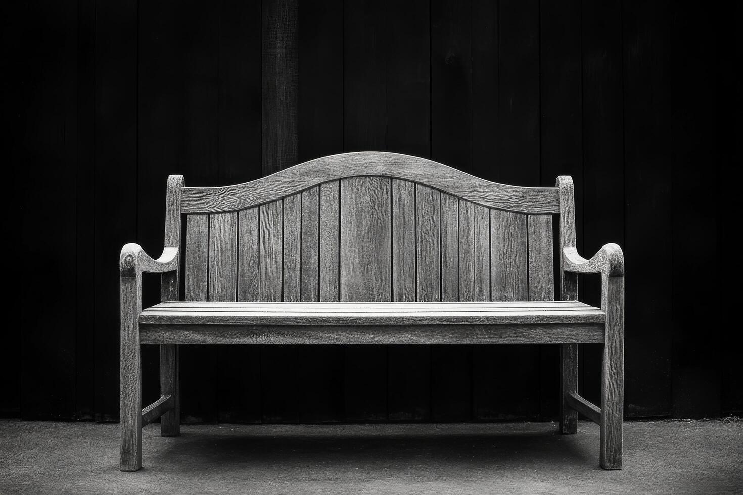A black and white photo of a bench sitting in front of a wall