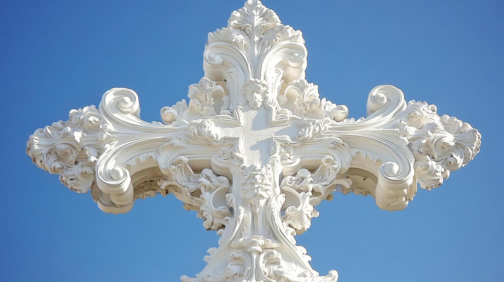 Ornate white cross against a clear blue sky highlighting intricate design details photo