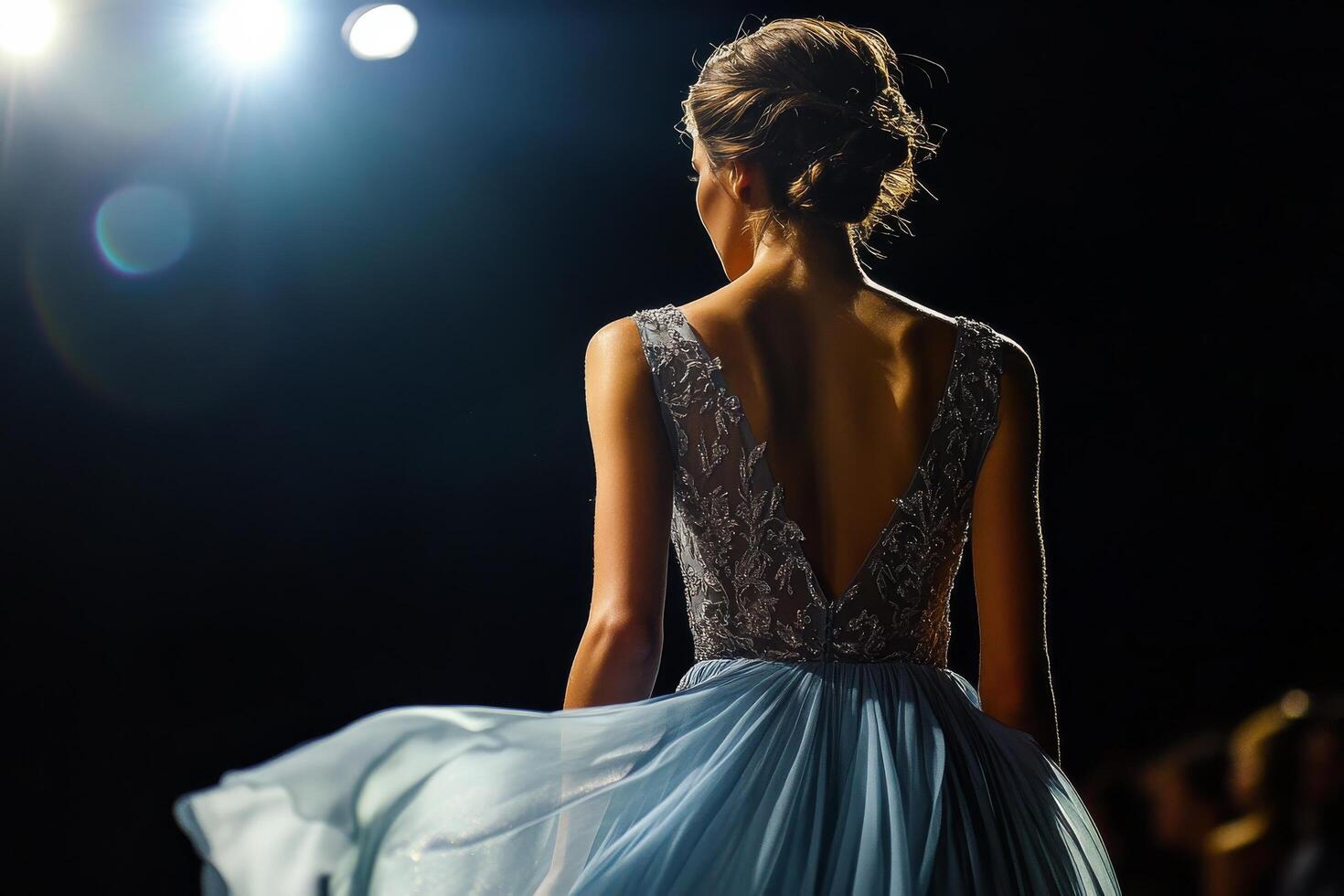 A woman in a blue dress walking down the runway photo