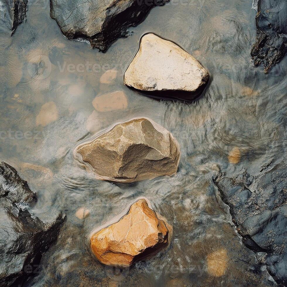Rocks varying in color and size sit in flowing water photo