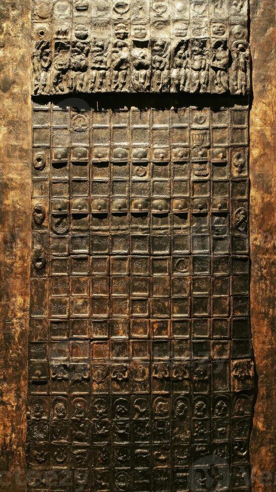 Carved stone panel displaying people and grid of symbols photo