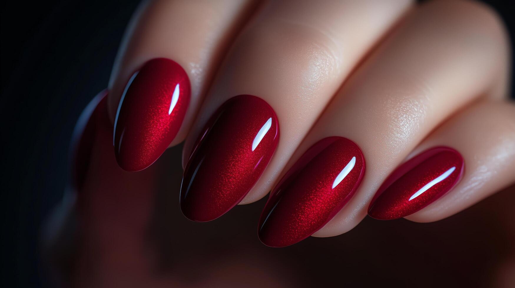 Elegant red nails with glossy finish displayed on a hand against a dark background photo