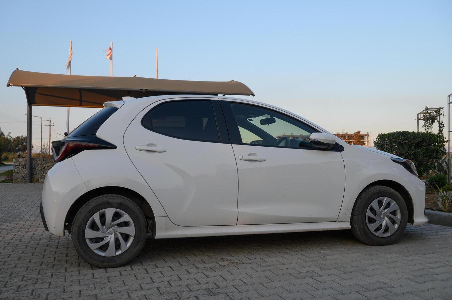 Gaziveren Cyprus -30.01.2025 Sleek white hatchback parked in the evening sunlight near a modern building photo