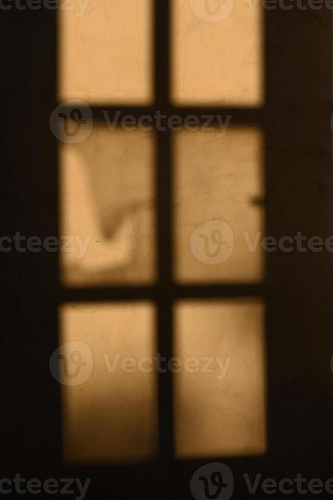 Shadows dancing through elegant windowpanes at dusk, hinting at stories untold in the warm glow of twilight photo