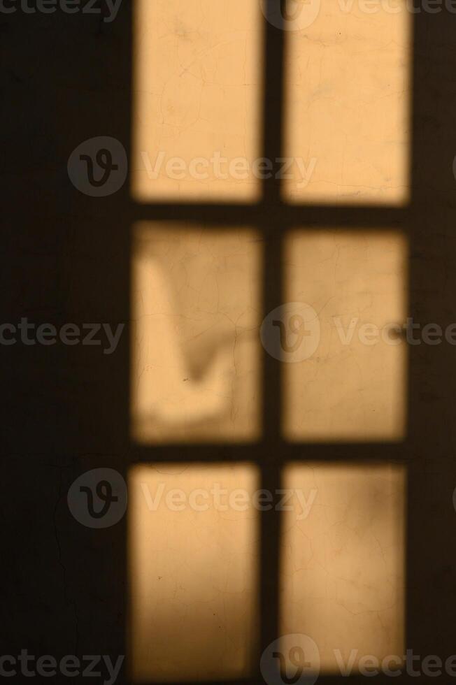 Soft sunlight filters through a weathered window casting shadows in a quiet room photo