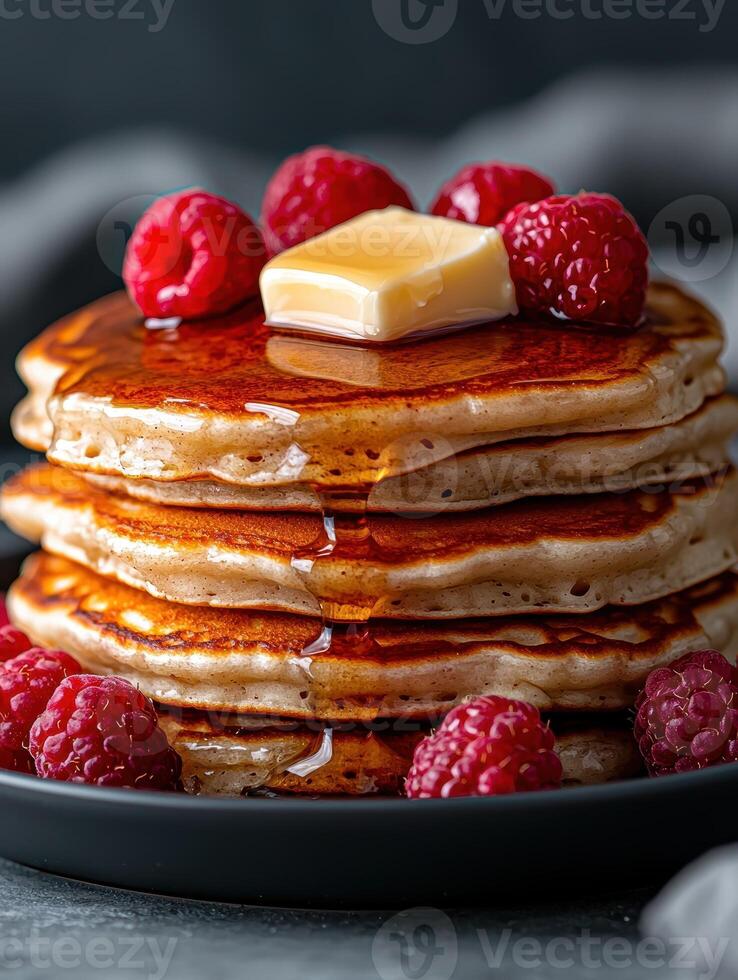 Stack of pancakes with butter, syrup, and raspberries photo