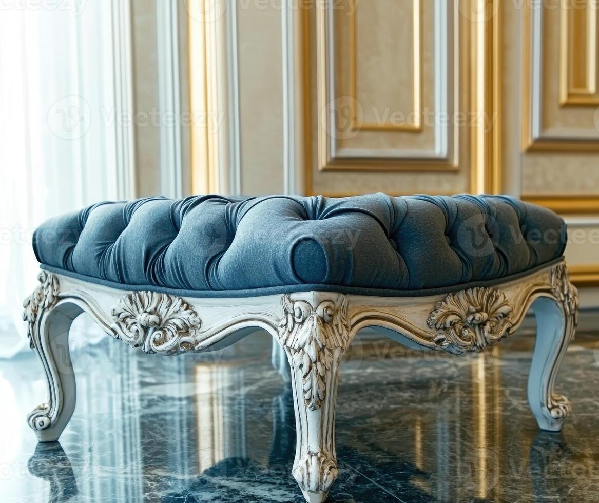 Elegant blue tufted ottoman with ornate white legs in a luxurious interior photo
