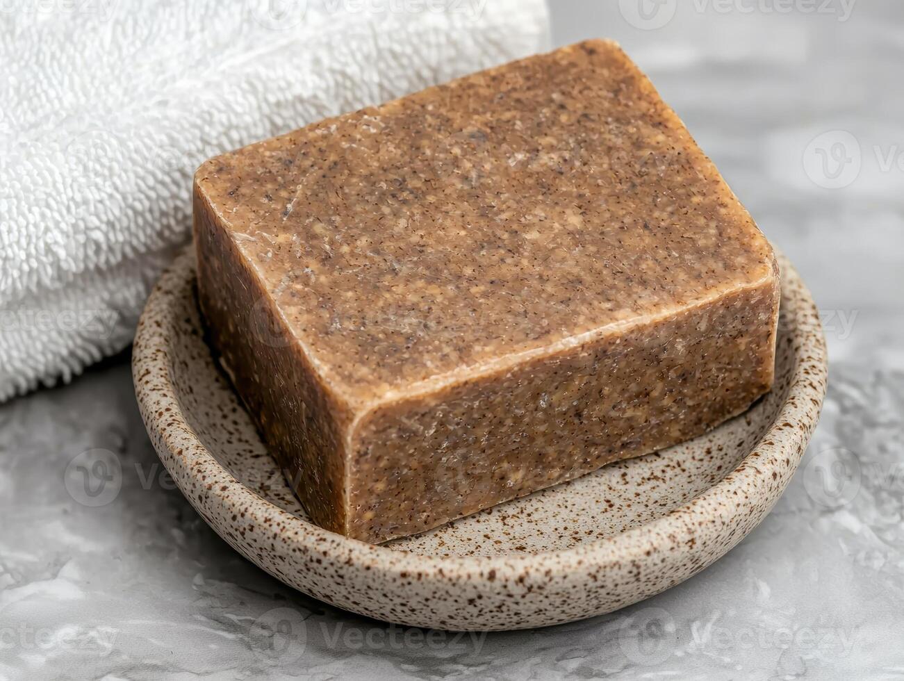 A bar of natural soap sits on a small dish next to a towel photo