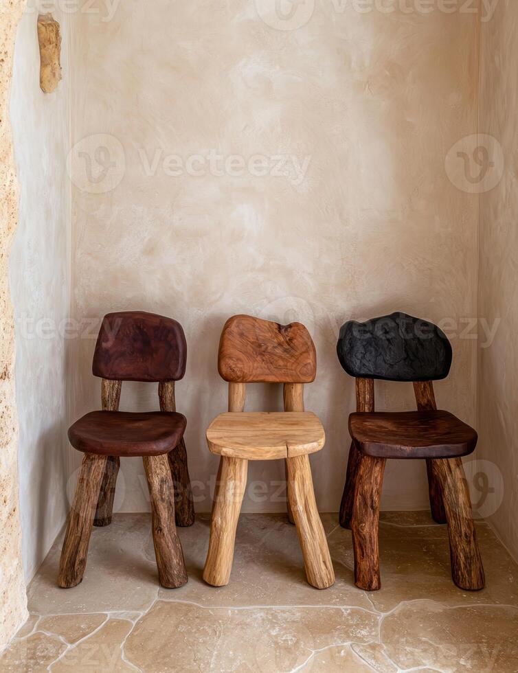 Three rustic wooden chairs sit in a corner of a room with textured walls photo
