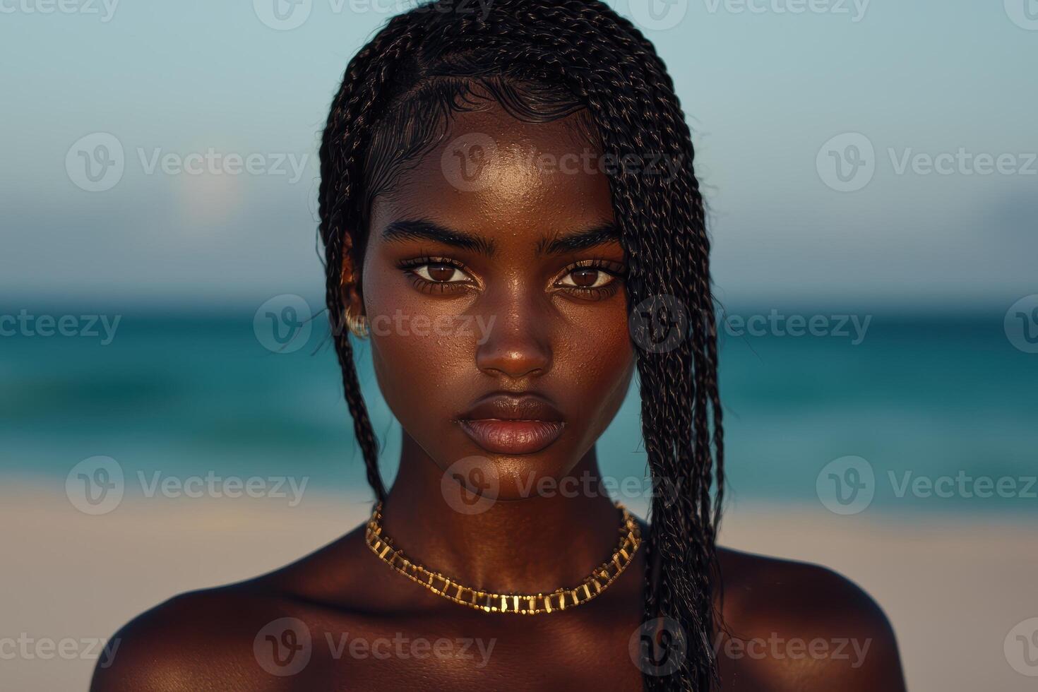 Portrait of a beautiful woman with braids and a gold necklace on a beach photo