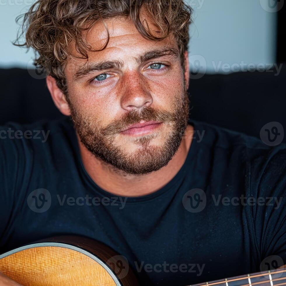 A man with a guitar looking at the camera photo