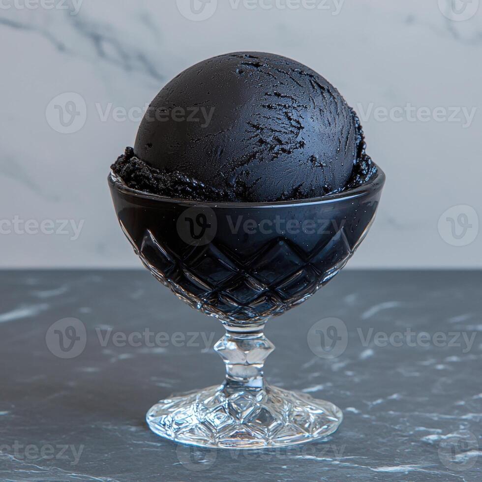 A scoop of black ice cream in a glass bowl photo