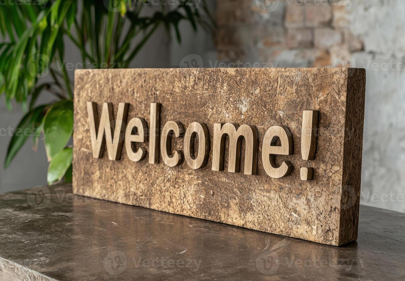 A wooden welcome sign on a table with a plant in the background photo