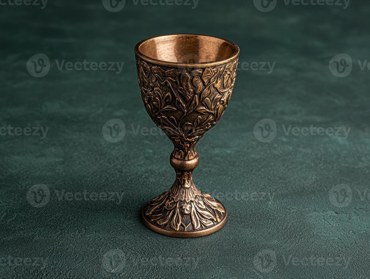 An ornate bronze goblet on a textured green surface photo