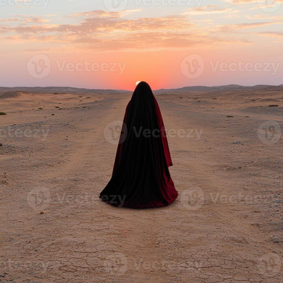 Person in black robe walking in desert at sunset photo