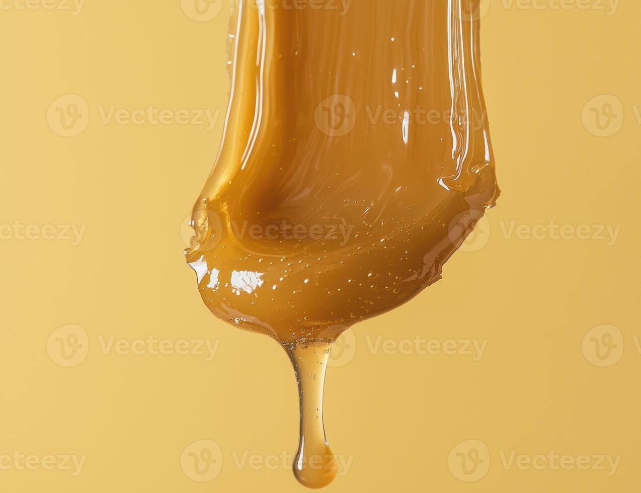 Golden honey dripping down against a yellow background photo