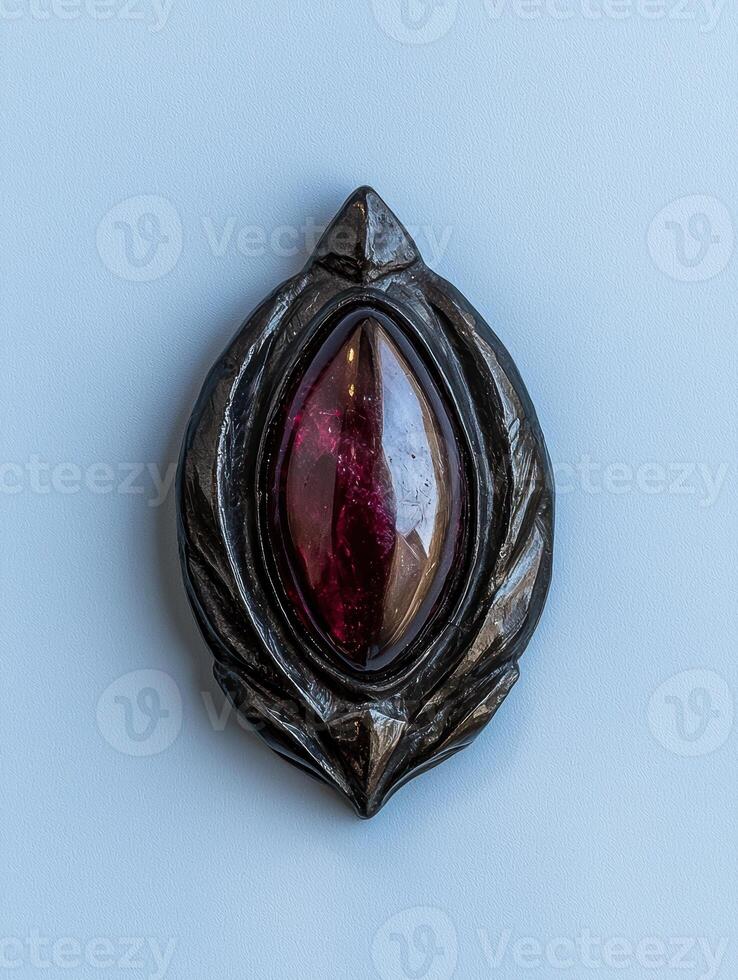 A dark metal pendant with a red gemstone photo