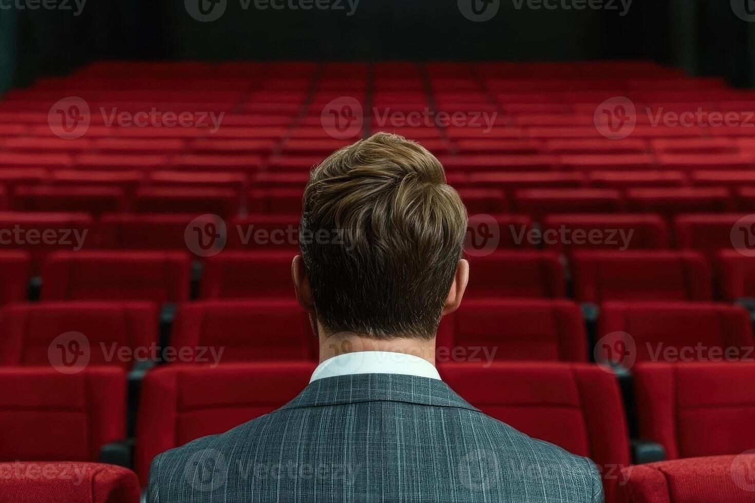 Man in a suit sitting in an empty theater photo