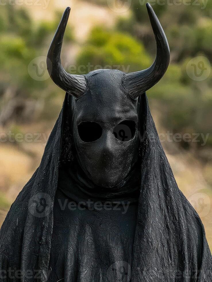 Mysterious figure in a black horned mask and cloak photo