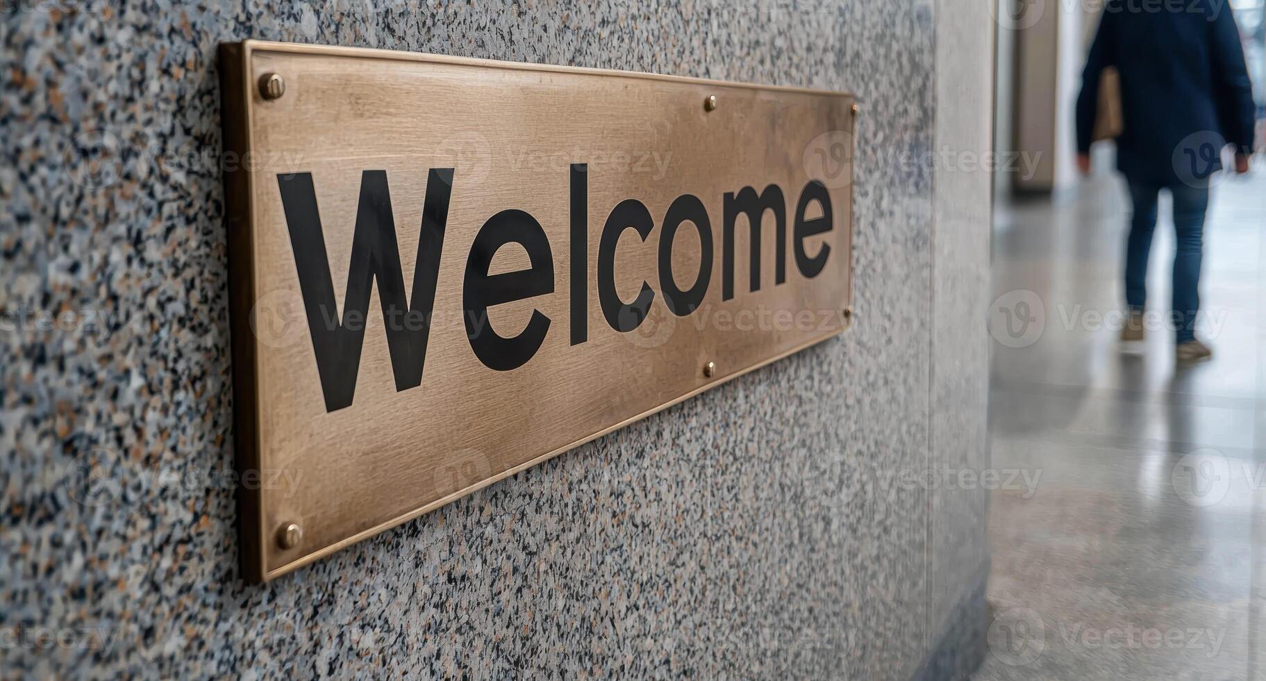 A welcome sign hangs on a wall in a building photo