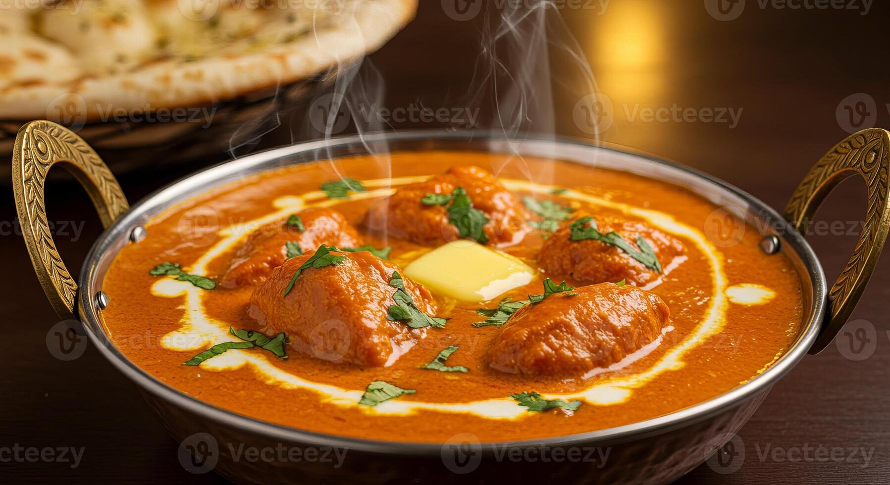 A bowl of curry with meat and bread on a table photo