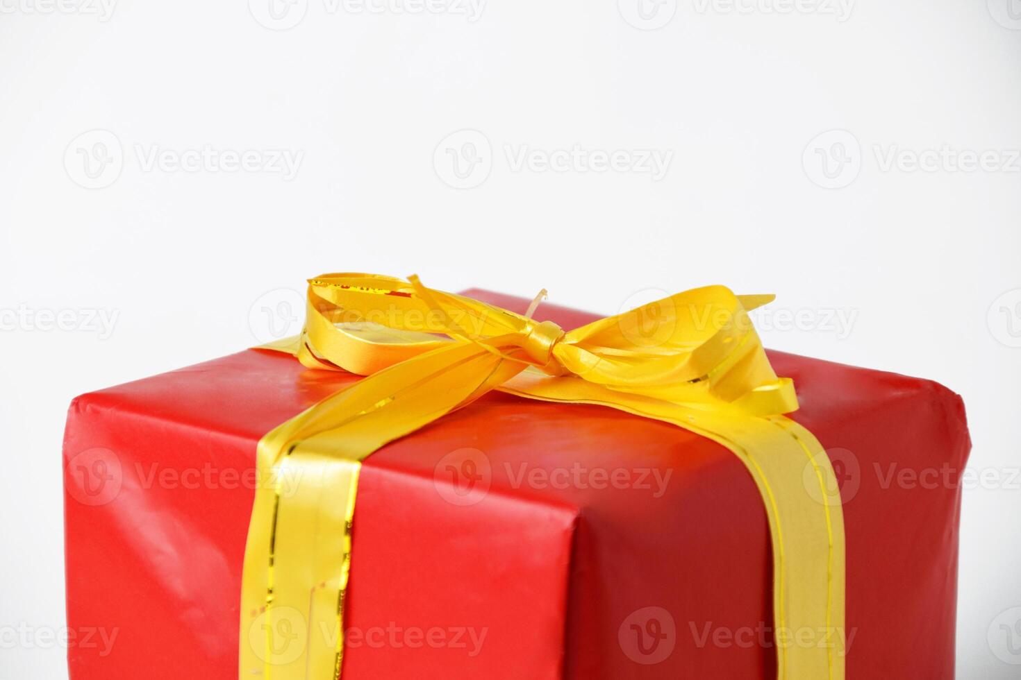 Closeup and top view photo of a red gift box with a yellow ribbon