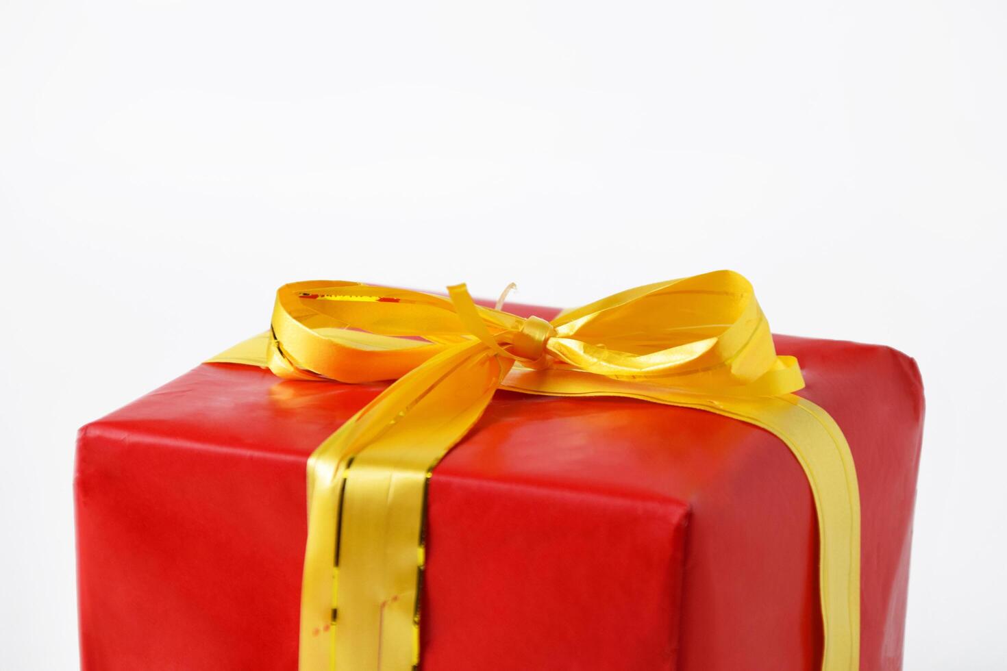 Red gift box wrapped with a yellow ribbon captured in top view and closeup photo