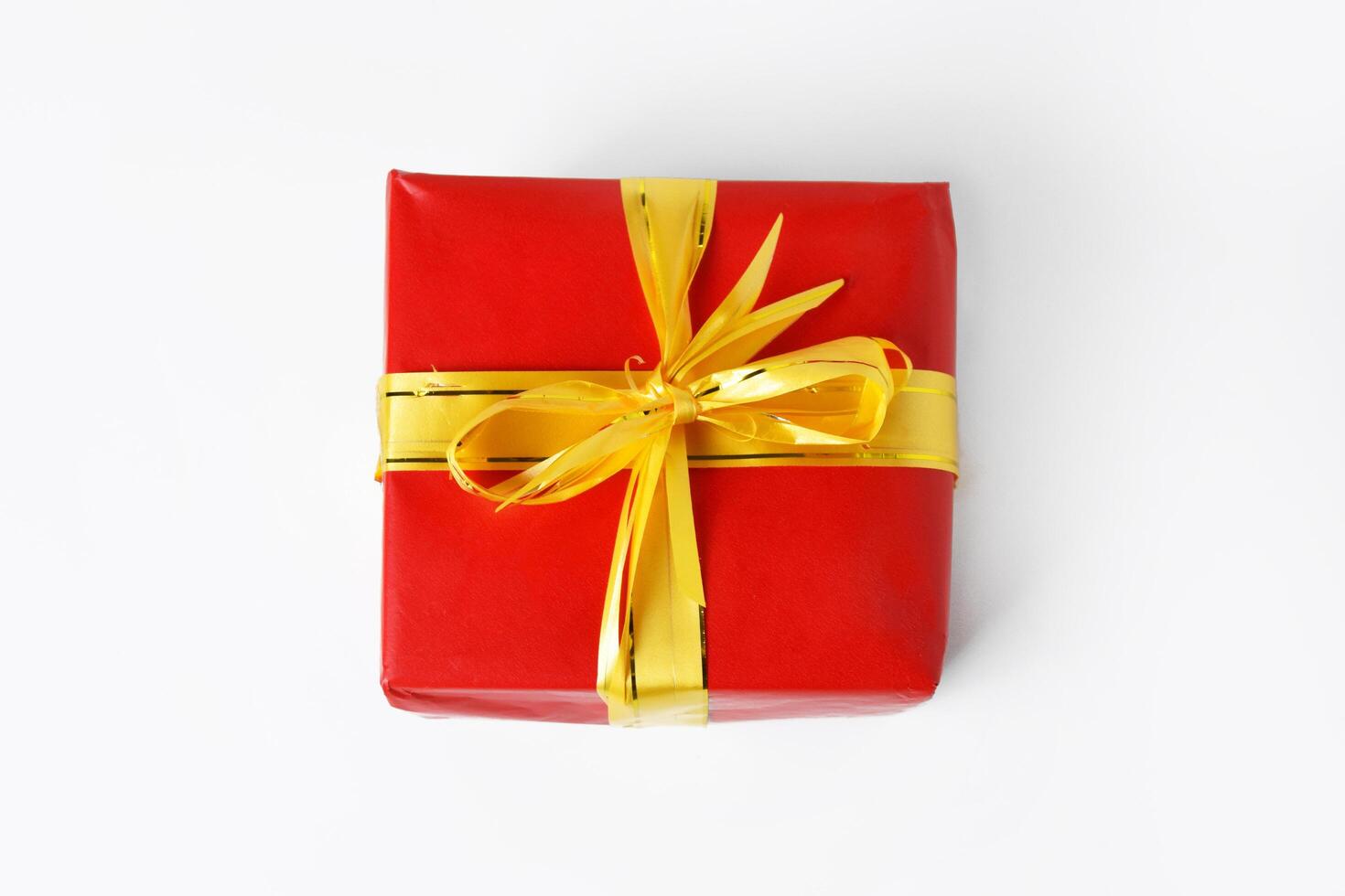 Top view shot of a red gift box with a yellow-gold ribbon for Christmas and New Year photo