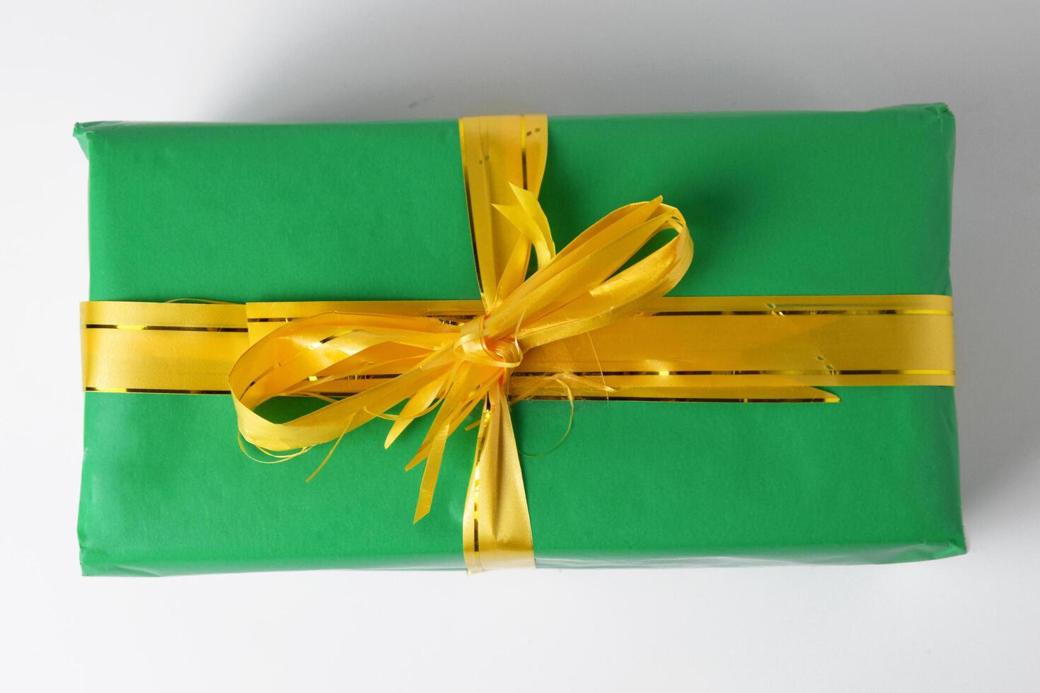 Overhead Shot of a Green Gift Box Wrapped with a Gold Ribbon photo