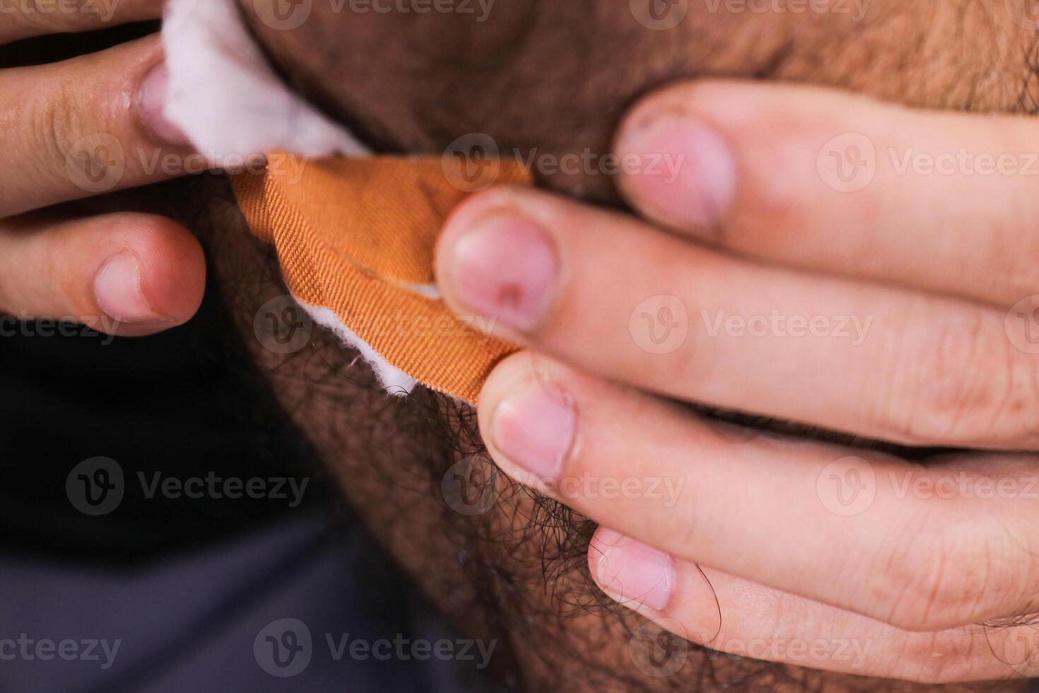 Close up of applying a bandage to an injured knee. The person is using a small, adhesive bandage and cotton gauze on skin. photo
