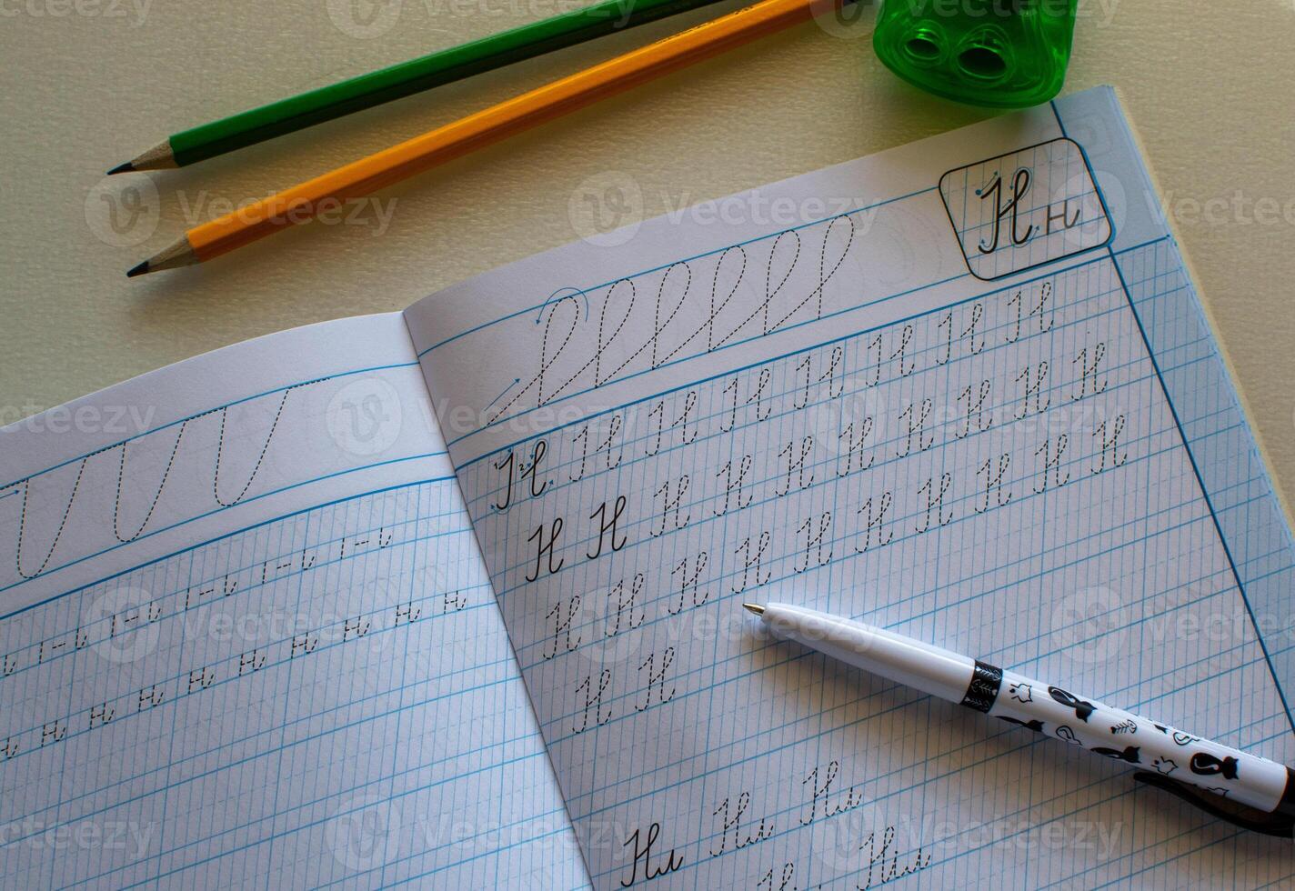 View of a notebook for practicing writing letters, notebook and pencils photo