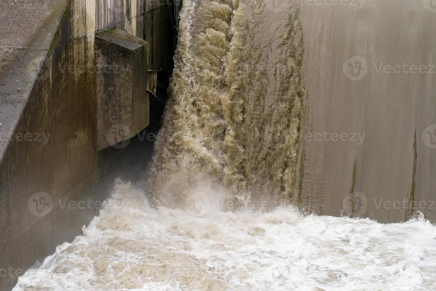 Discharge of water at the dam during flood. Powerful water flow. photo