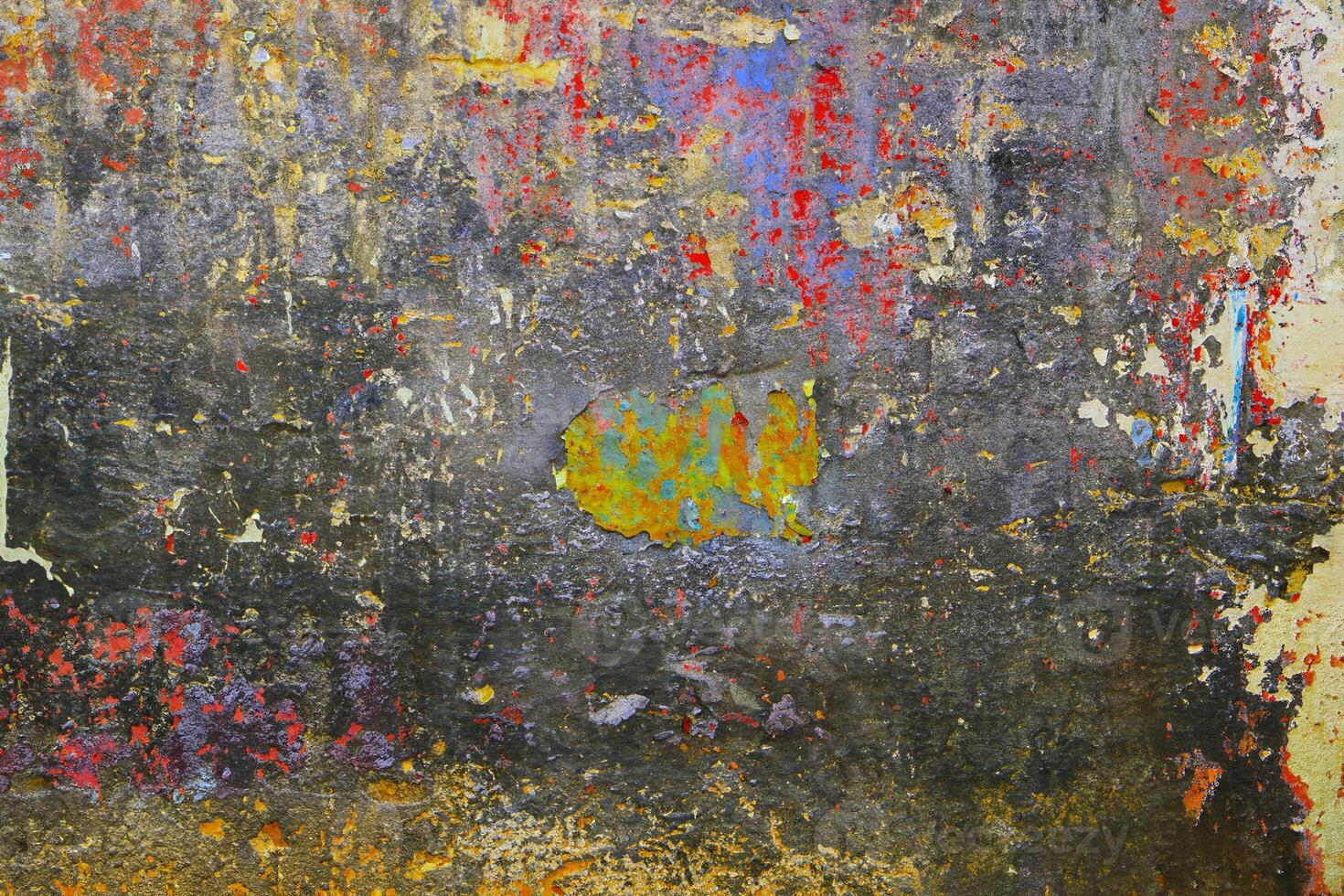 A vibrant abstract texture of a weathered wall with layers of peeling paint in red, yellow, and blue tones. photo