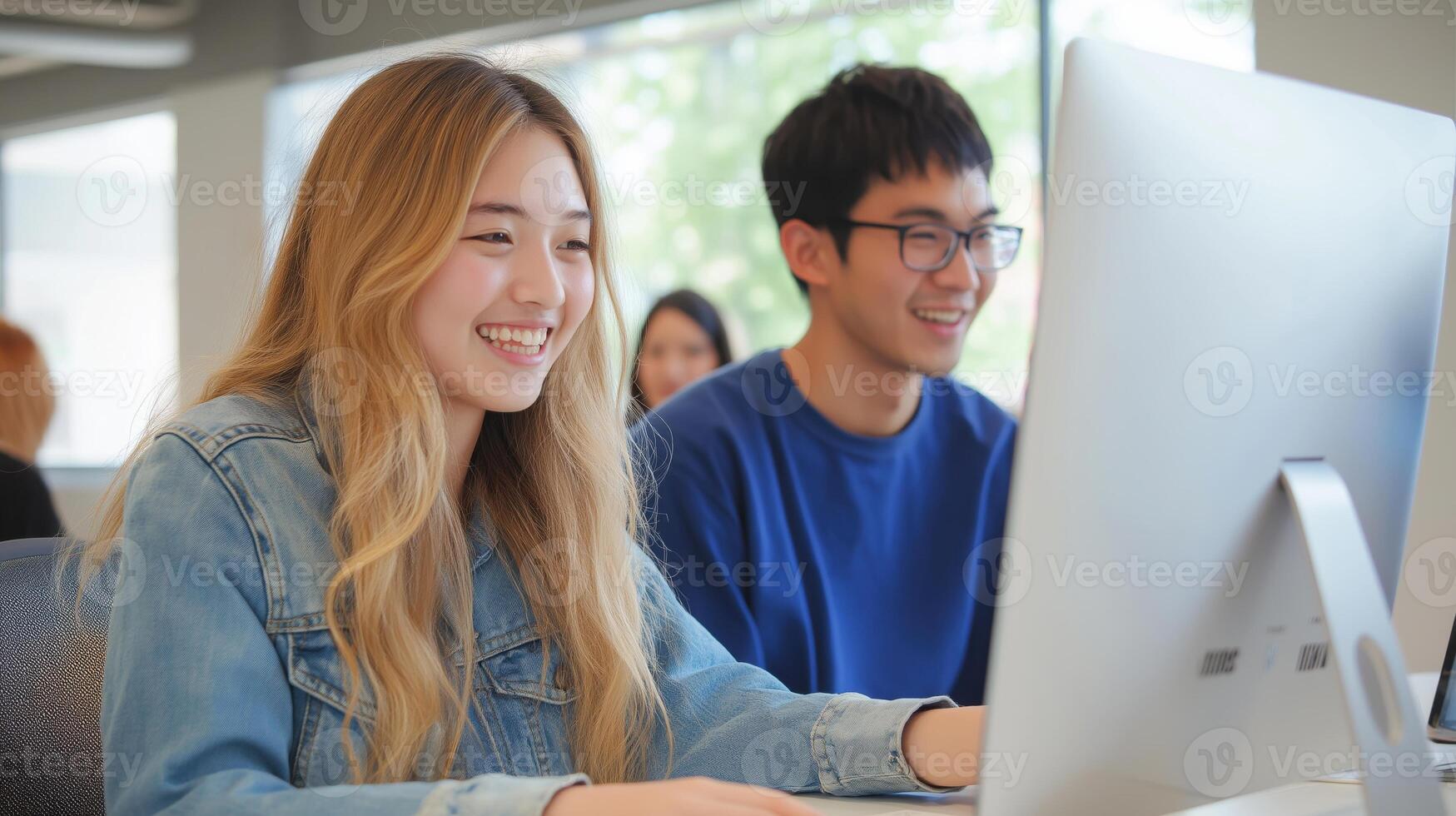a young asia couple sitting at a desk in front of a computer monitor photo