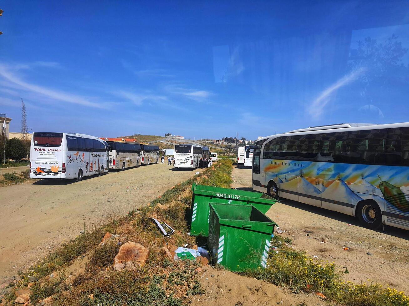 Mecca, Saudi Arabia on 24 February 2024. Parked Tour Buses Sunny Day Landscape Green Bins photo