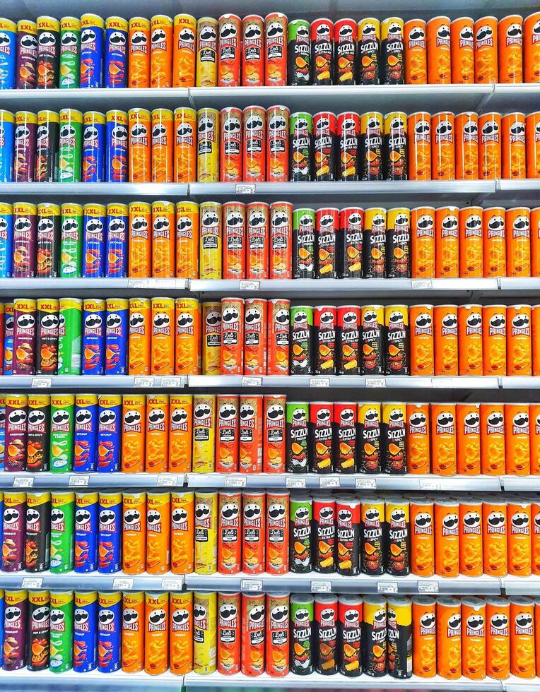 Madinah, Saudi Arabia on 28 February 2024. Colorful Pringles Cans Stacked Shelves Grocery Store Display photo
