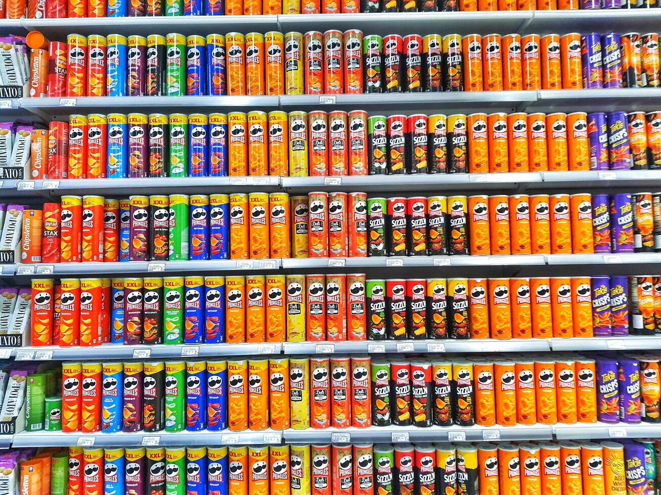 Madinah, Saudi Arabia on 28 February 2024. Colorful Snack Chip Cans Grocery Store Shelf Display photo