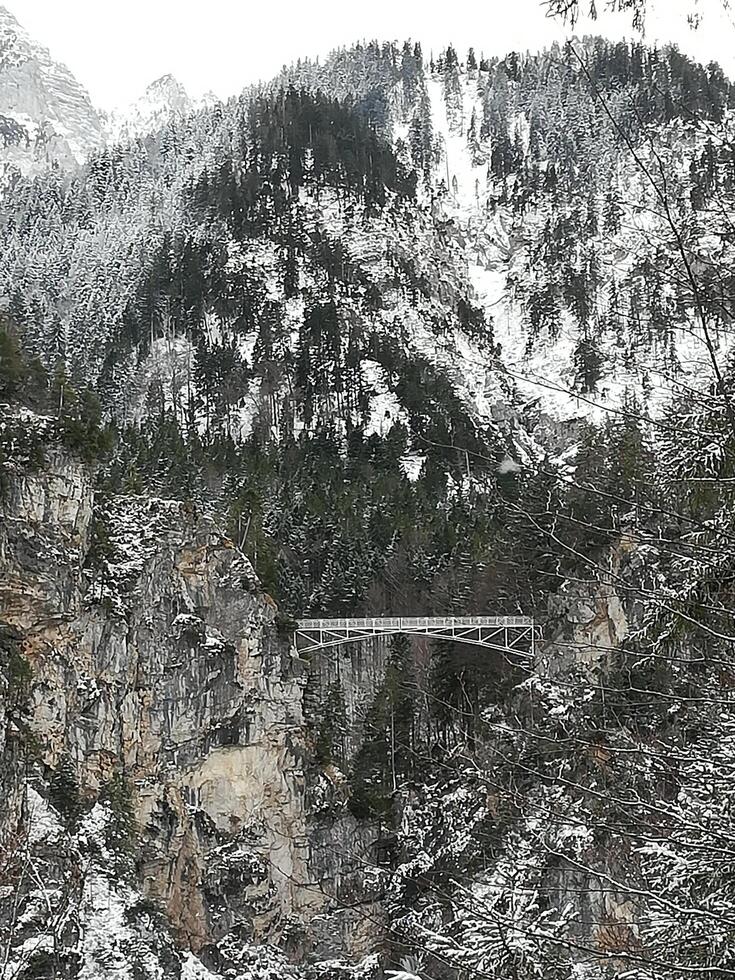 a suspension bridge between two snow-capped mountains photo